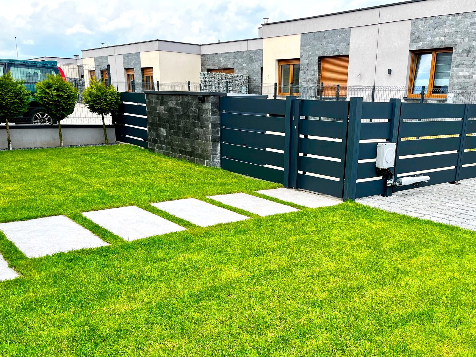 Ogrodzenie aluminiowe w odcieniu antracytu zamontowane w kamiennej podmurówce