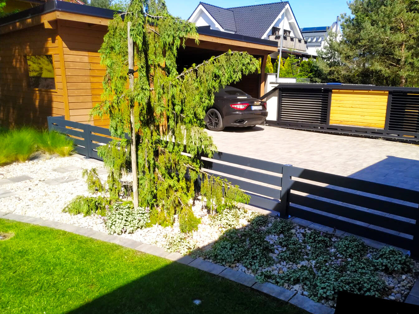 Aluminiowe ogrodzenie w ogrodzie, oddzielające strefę garażową i podjazd od ogrodu.