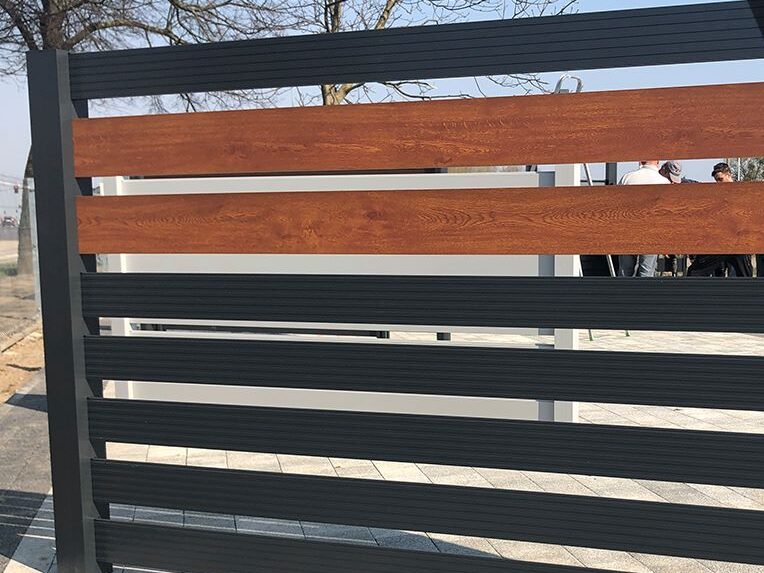 Przykład ogrodzenia aluminiowego z częścią imitującą drewno, kolor czerwono-antracytowy.