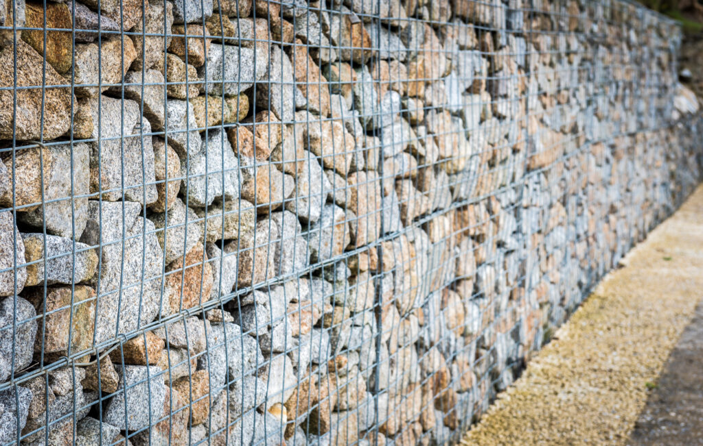 Na zdjęciu jest ogrodzenie gabionowe - stalowa siatka wypełniona kamieniami.