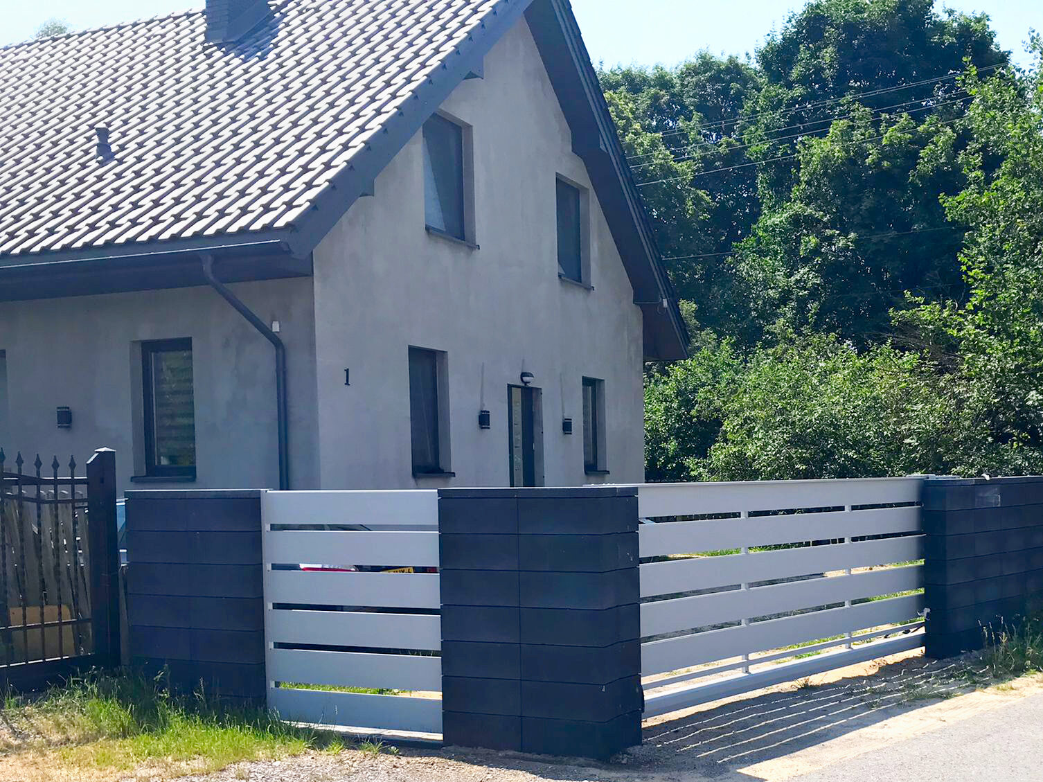 Ogrodzenie aluminiowe w kolorze białym z ciemnoszarymi przęsłami.